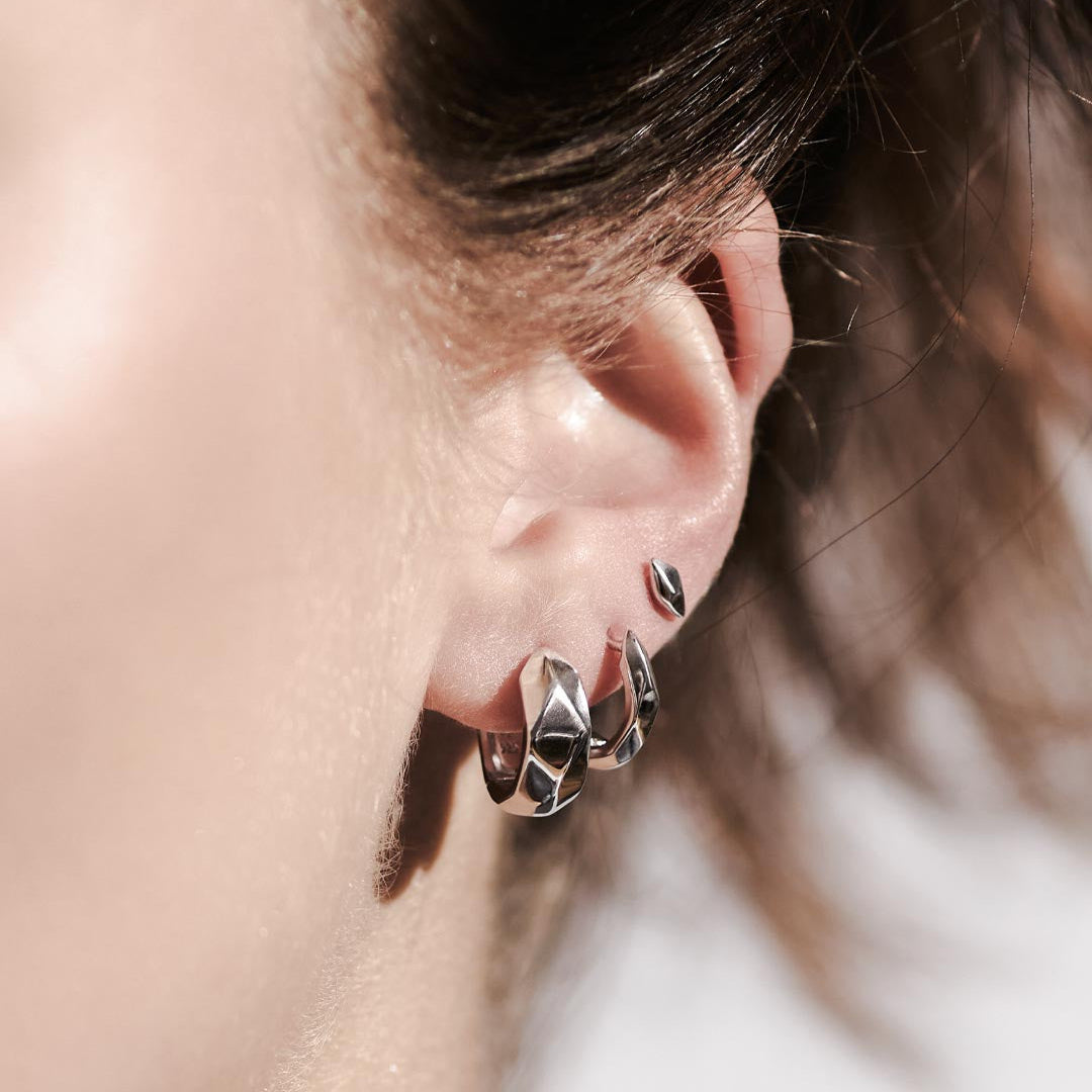 The Kit Heath Glint Geo Wide Hoop Earrings feature a bold Sterling Silver silhouette with faceted detailing. A statement hoop design balancing modern structure with everyday wearability.